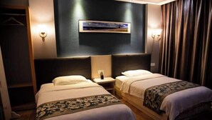 A hotel room with two beds, a dark wall with a framed picture, and a curtain on the right. - Xuan En Jingyi Sunshine Inn (Xuan'en)