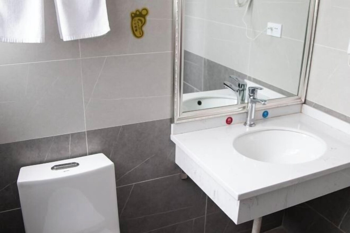 Une salle de bain avec un lavabo blanc, un miroir et des toilettes.
