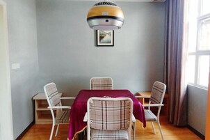 Un comedor con una mesa y cuatro sillas, un respiradero en el techo y un cuadro en la pared.