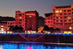 Un edificio de varios pisos con letreros iluminados y una escalera que lleva a la entrada.