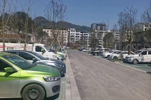 Un estacionamiento con automóviles, cielo despejado y edificios al fondo.