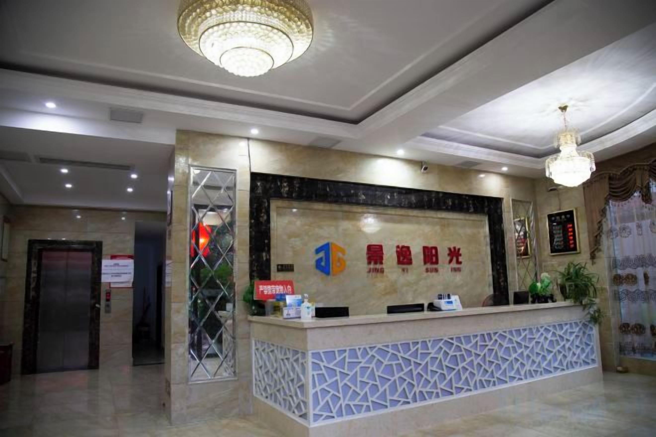 Ein Hotel-Empfangsbereich mit einer Rezeption, einer Kristallleuchter und einem Schild mit chinesischen Schriftzeichen.