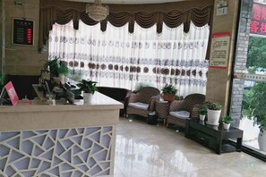 A reception area with a reception desk, seating area, and potted plants. - Xuan En Jingyi Sunshine Inn (Xuan'en)