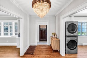 Ein geräumiger Flur mit einer großen Chandelier, einer Waschmaschine und einem Trockner sowie Blick ins Freie.
