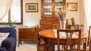 A dining area with a wooden table, chairs, and a cabinet with glass doors. - Villa Ontanelli - 500mt from the sea (Marciana Marina)