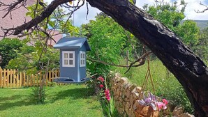 A small blue birdhouse in a garden with a stone wall and a wooden fence. - Villa Ontanelli - 500mt from the sea (Marciana Marina)