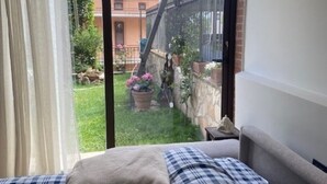 Ein Schlafzimmer mit einer großen Glasschiebetür, die zu einem kleinen Garten mit Topfpflanzen und einer Ziegelmauer führt.