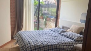 Ein Schlafzimmer mit einem Bett, einem Sessel und einem Fenster mit Vorhängen.