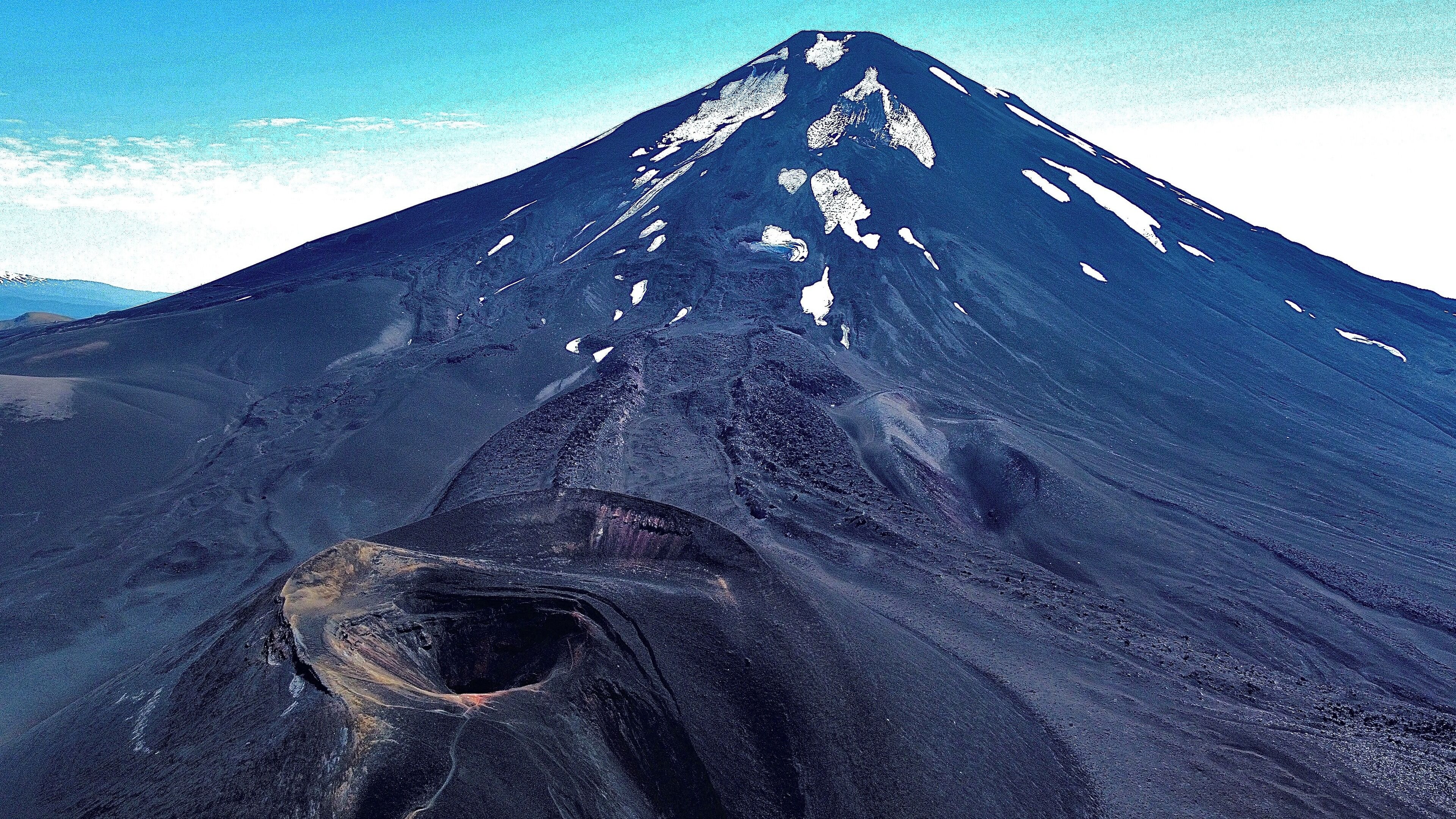 Una montaña con un pico destacado y un cráter profundo en su base.
