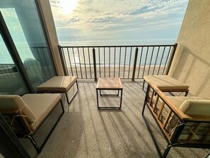 A balcony with a view of the sea, furnished with two cushioned chairs and a wooden table. - Oceanfront Oasis | Indoor Pool | Hot Tub | Deck (Ocean City)