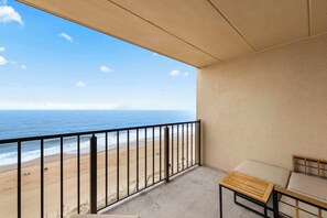 Un balcone con vista sulla spiaggia, un tavolino e un divano.