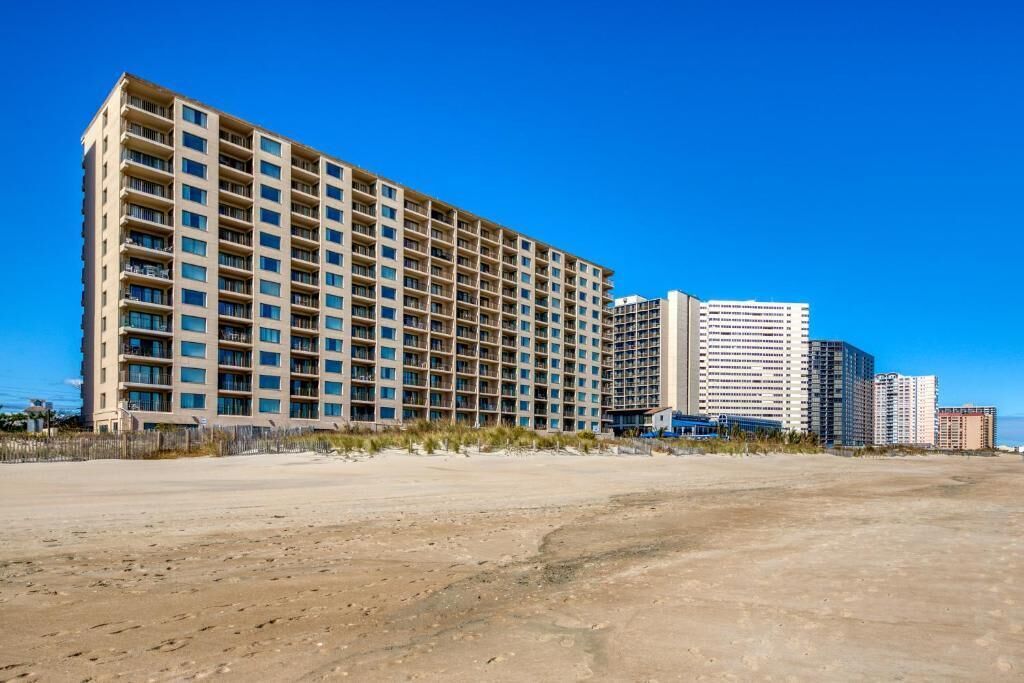 Um hotel com vários andares e fachada uniforme, situado perto de uma praia com areal.