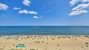 Een strand met parasols en mensen, een heldere lucht en de oceaan.