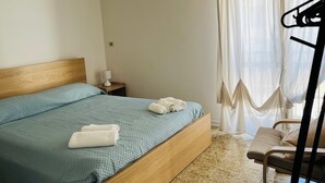A hotel room with a bed, a nightstand, a lamp, a chair, and a window with curtains. - La Casa Sul Pontile (Marina di Vasto)
