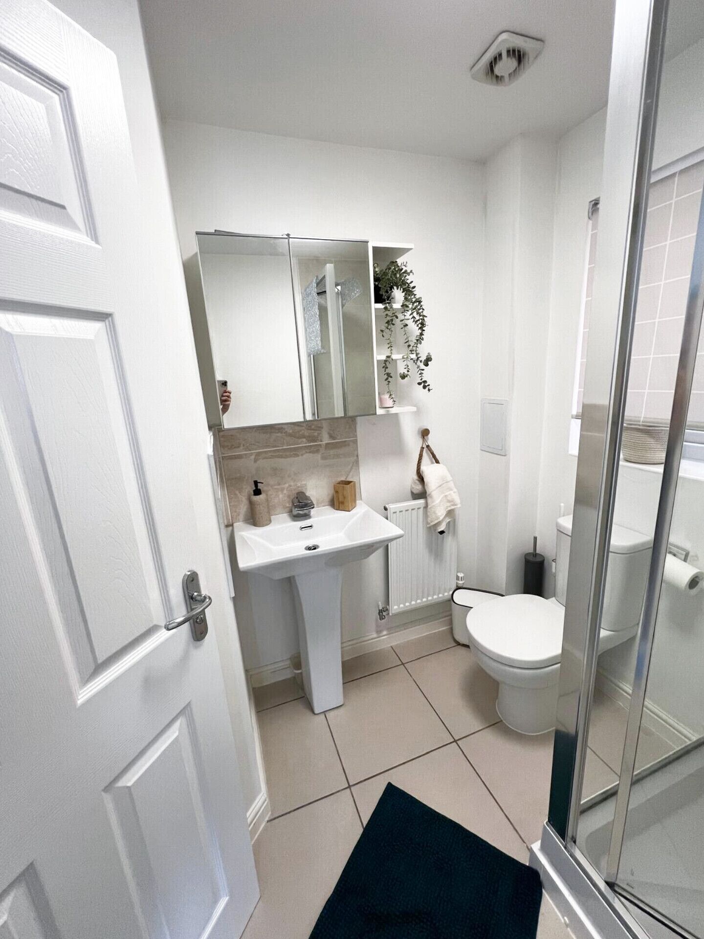 A bathroom with a white sink, mirror, and toilet. There is a shower area with a glass door.
