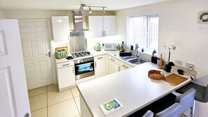 A modern kitchen with a central island, stainless steel appliances, and bar stools. - Stay Sleep Rest - Brockwell Park (Hull)