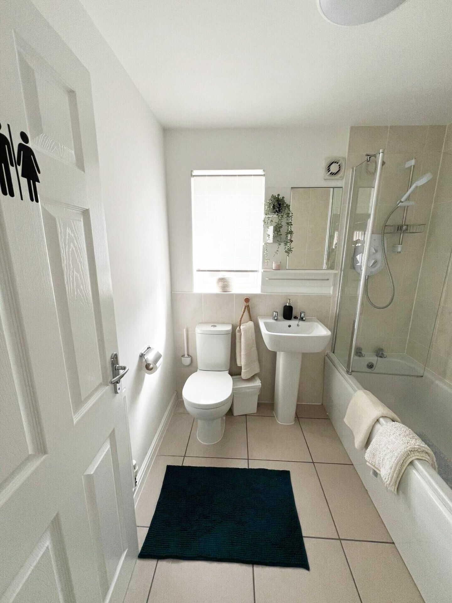 A compact bathroom with a toilet, sink, and shower.
