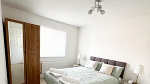 A bedroom with a bed, bedside tables, a wardrobe, and a window with blinds. - Stay Sleep Rest - Brockwell Park (Hull)