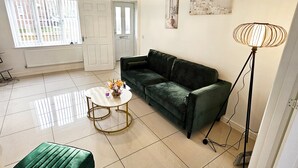 A modern living room with a green sofa, a round coffee table, and a floor lamp. - Stay Sleep Rest - Brockwell Park (Hull)