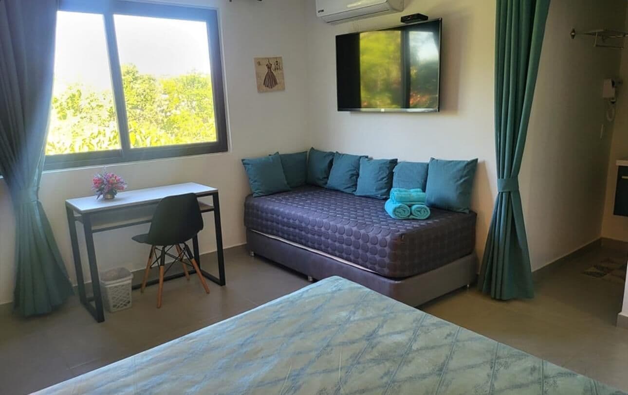 Makuuhuoneessa on sänky, työpöytä, tuoli, ikkuna ja seinälle asennettu televisio.