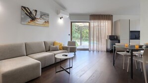 Una sala de estar moderna con un sofá, una mesa redonda pequeña y un comedor con televisión y microondas.