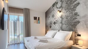Un dormitorio moderno con una cama grande, vistas al exterior a través de una puerta corrediza y una pared decorativa con estampado floral.