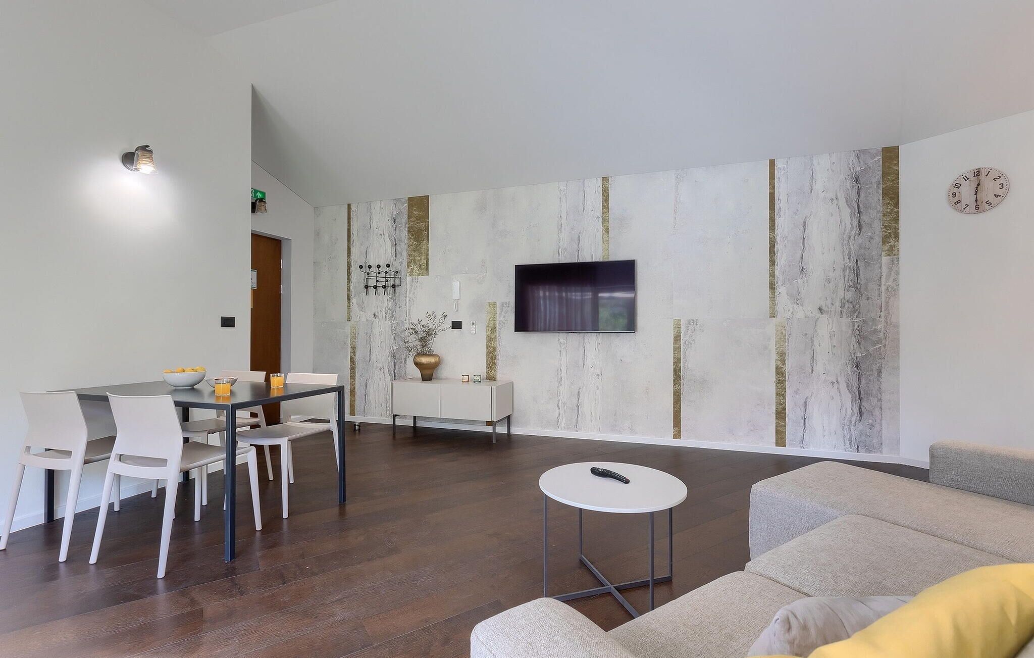 A modern living room with a sofa, a coffee table, and a dining area with chairs and a table.
