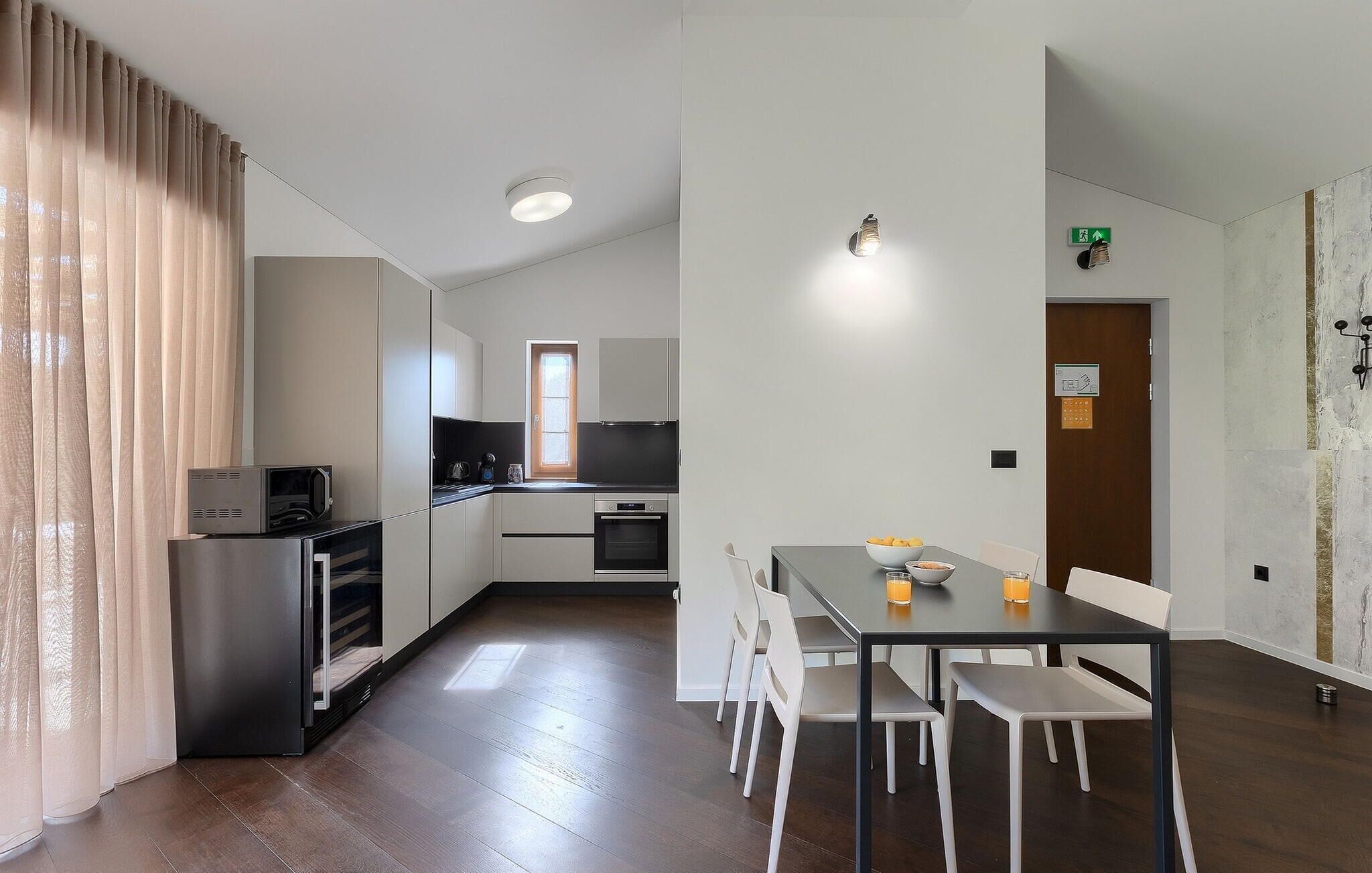 A modern kitchen with a dining area, including a table with chairs and a microwave.