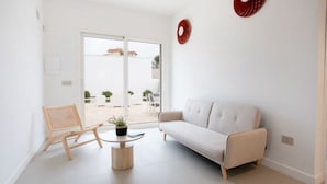 Un salon moderne avec un canapé, une chaise en bois, une petite table ronde et une plante en pot.