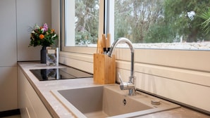 Une cuisine moderne dotée d’une grande fenêtre, d’un évier encastré et d’un porte-ustensiles en bois.
