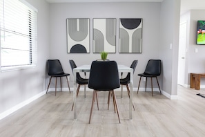 A dining area with a white table, black chairs, and a potted plant.