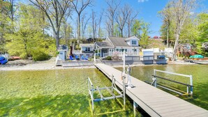 A lakeside property with a dock, clear water, and a house with a covered patio. - Waterfront Romulus Getaway w/ Private Dock! (Romulus)
