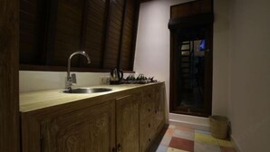 A kitchen with wooden cabinets, a stainless steel sink, and a window with a view of the outside. - Green Bird Villa (Bali)