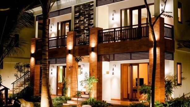A multi-story hotel with a modern design, featuring balconies, a well-lit entrance, and a landscaped garden. - Green Bird Villa (Bali)