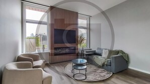 Ein modernes Wohnzimmer mit einem grauen Sofa, einem runden Couchtisch und einem an einer Holzplatte montierten Fernseher.