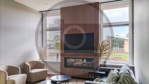 Ein modernes Wohnzimmer mit großem Fenster, einer Couch, zwei Sesseln und einem kleinen Tisch.