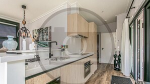 Eine moderne Küche mit einer zentralen Kochinsel, Spüle aus Edelstahl und Holzschränken.