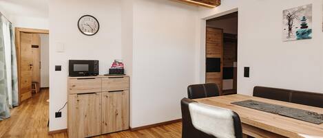 Un comedor moderno con una mesa y sillas de madera, un reloj en la pared y un mueble de madera con microondas.