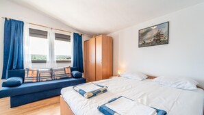 Et soveværelse med seng, sofa, garderobeskab og et billede på væggen.