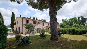 A villa with a garden, outdoor seating, and a large tree. - Apartment 'Antichi Palmenti - Mirto' with Shared Garden and Air Conditioning (San Vincenzo)