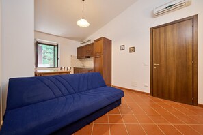 Ein Zimmer mit einem blauen Sofa, einer Küchenzeile und einer Holztür.