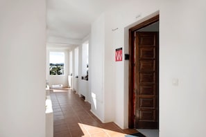 A corridor with white walls, a wooden door, and a tiled floor. - Vacation Apartment 'Los Molinos 4306' with Sea View, Private Pool and Wi-Fi (Costa Teguise)