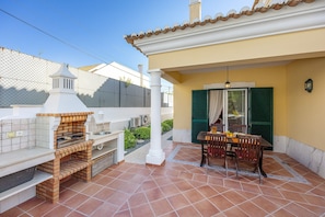 An outdoor patio with a brick oven, a dining table with chairs, and a covered seating area. - Villa 'Tucha' with Private Pool, Wi-Fi and Air Conditioning (Alvor)