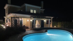 Una casa con piscina durante la noche.