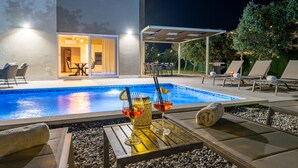 Ein Pool mit Liegestühlen und einer überdachten Terrassenbereiches.