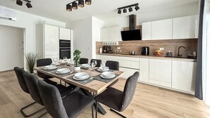 Eine moderne Küche mit weißen Schränken, einer Holzausziehtheke und einem eingebauten Backofen.
