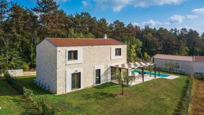 Ein Steinhhaus mit rotem Dach, einem Swimmingpool und einem Garten.