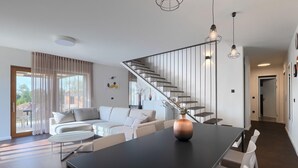 Ein modernes Wohnzimmer mit Sofa, Couchtisch und einem Essbereich mit Stühlen.