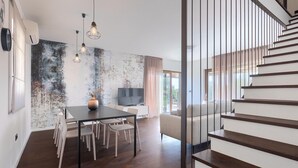 Ein modernes Wohnzimmer mit Essbereich, einer Treppe und einem großen Fenster.