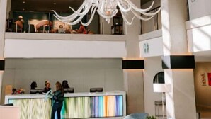 Eine großzügige Lobby mit einem modernen Kronleuchter, einer Rezeption und einer Sitzgelegenheit.